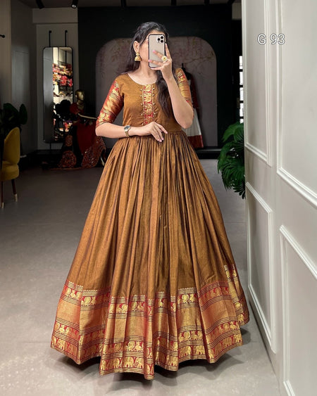 Woman in a traditional brown dress taking a mirror selfie in a room.