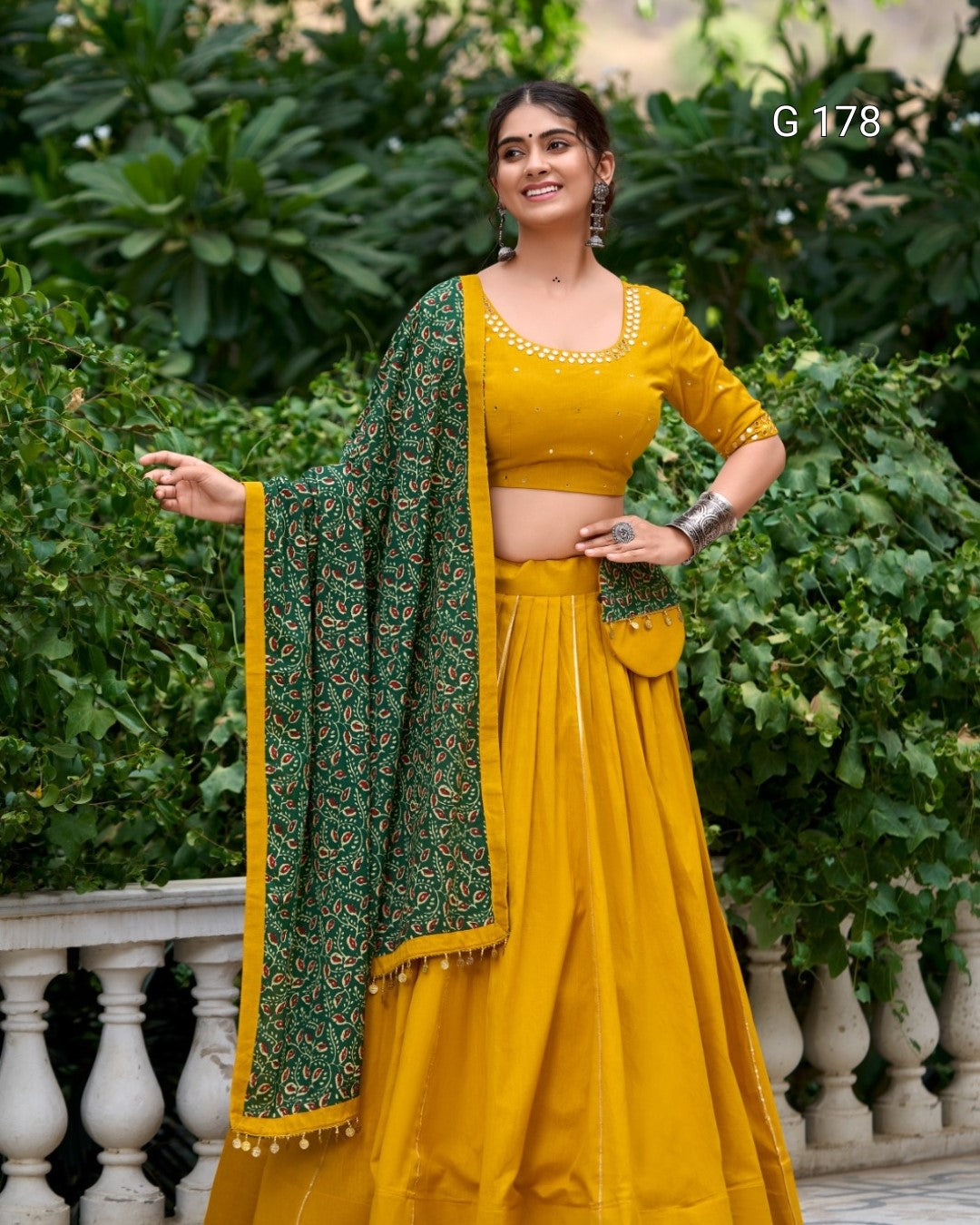 Woman wearing a yellow traditional outfit with a green dupatta against a green foliage background