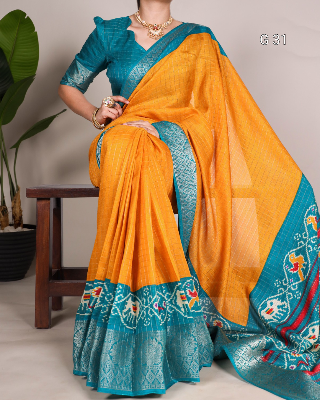 Woman wearing a traditional orange and blue saree with a plant in the background
