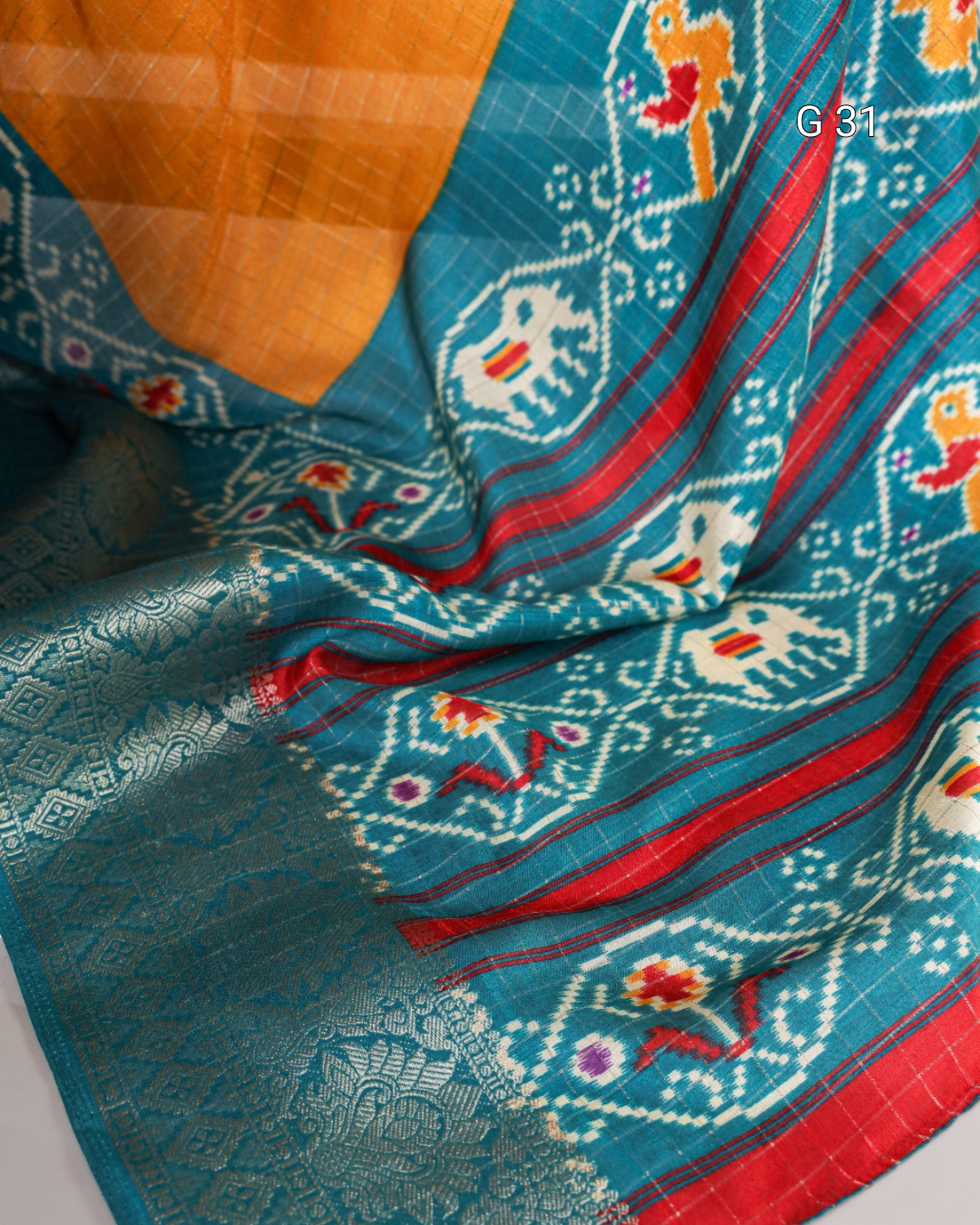 Close-up of a blue fabric with intricate patterns and orange and red accents.
