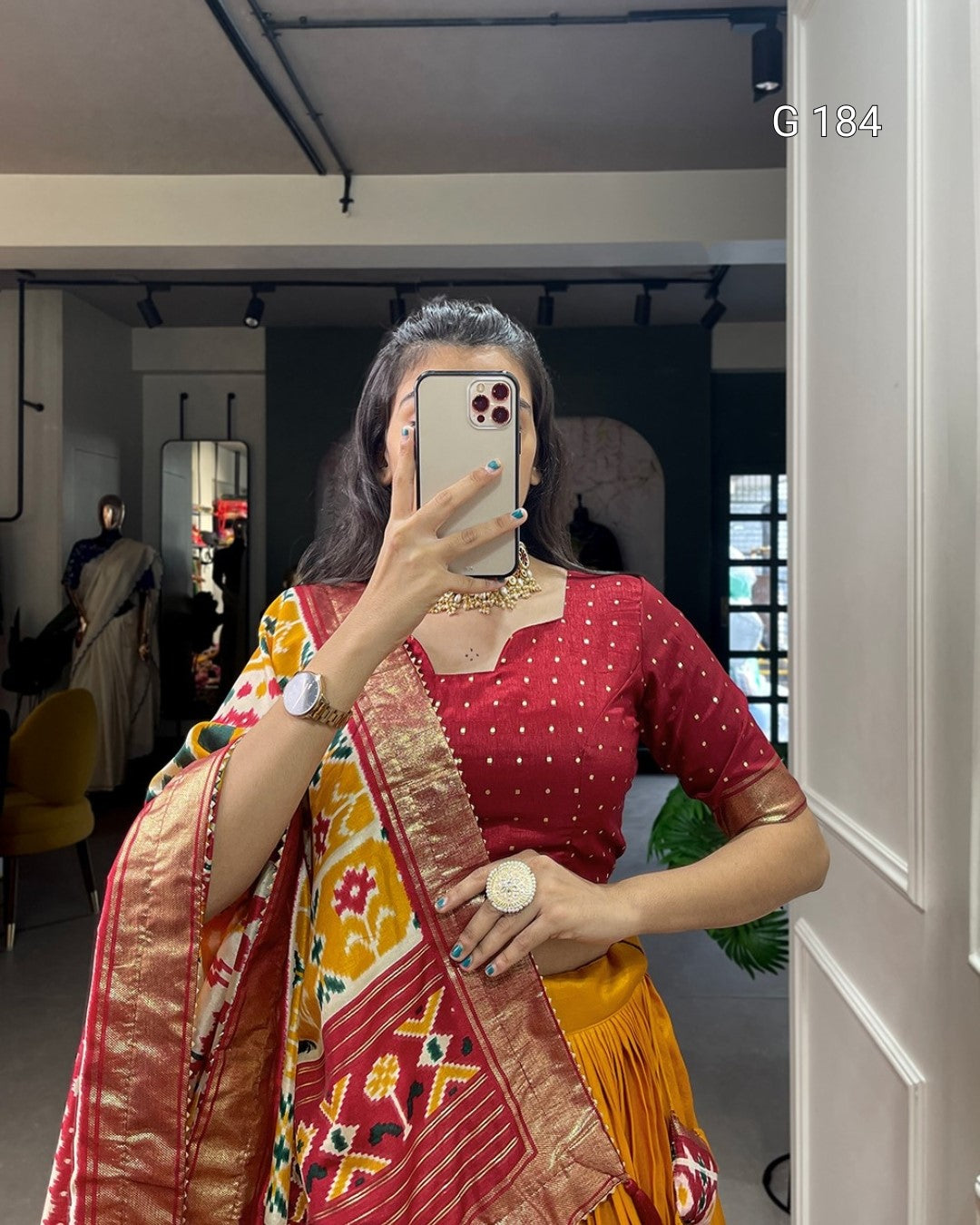 Person wearing a red blouse with a colorful saree in an indoor setting