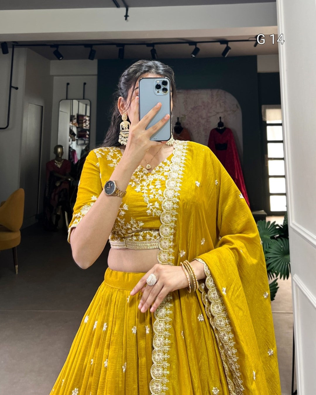 Person wearing a yellow traditional outfit with intricate designs, taking a mirror selfie.