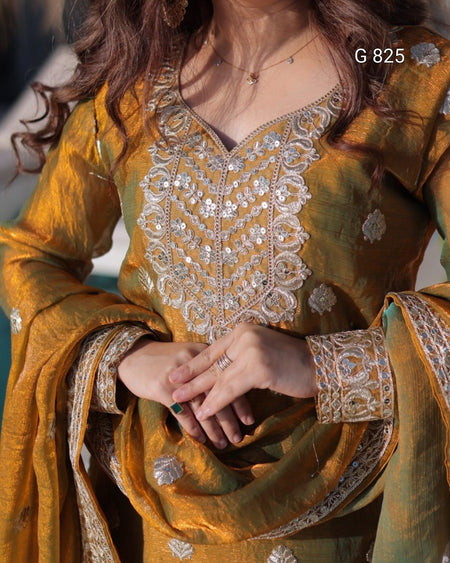 Close-up of a person wearing a mustard yellow embroidered traditional outfit with intricate patterns.