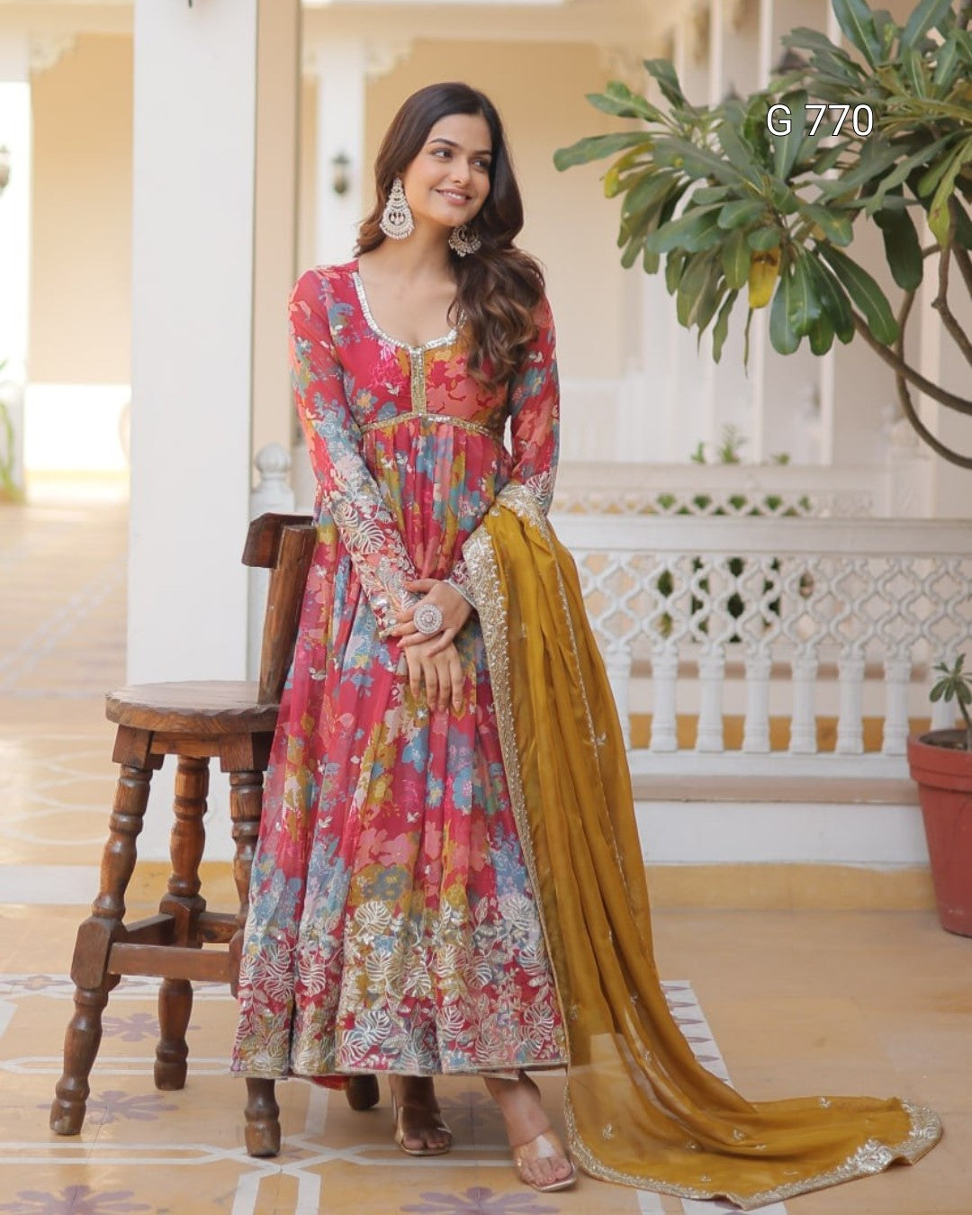 Woman in a colorful traditional outfit with a yellow dupatta in an indoor setting.