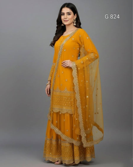 Woman wearing a mustard yellow traditional outfit with gold embroidery on a gray background
