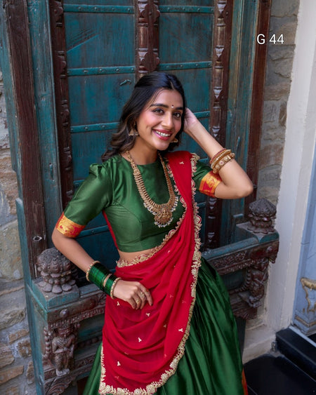 Woman in a green and red traditional outfit standing in front of an ornate door.