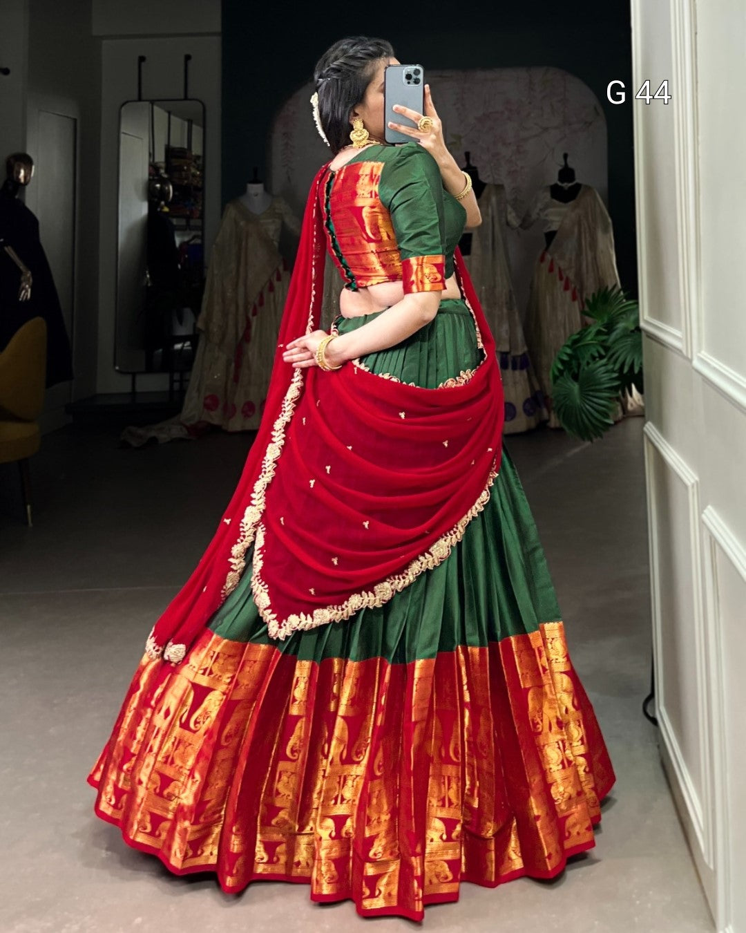 Person wearing a traditional green and red saree with a matching blouse, standing in a room.