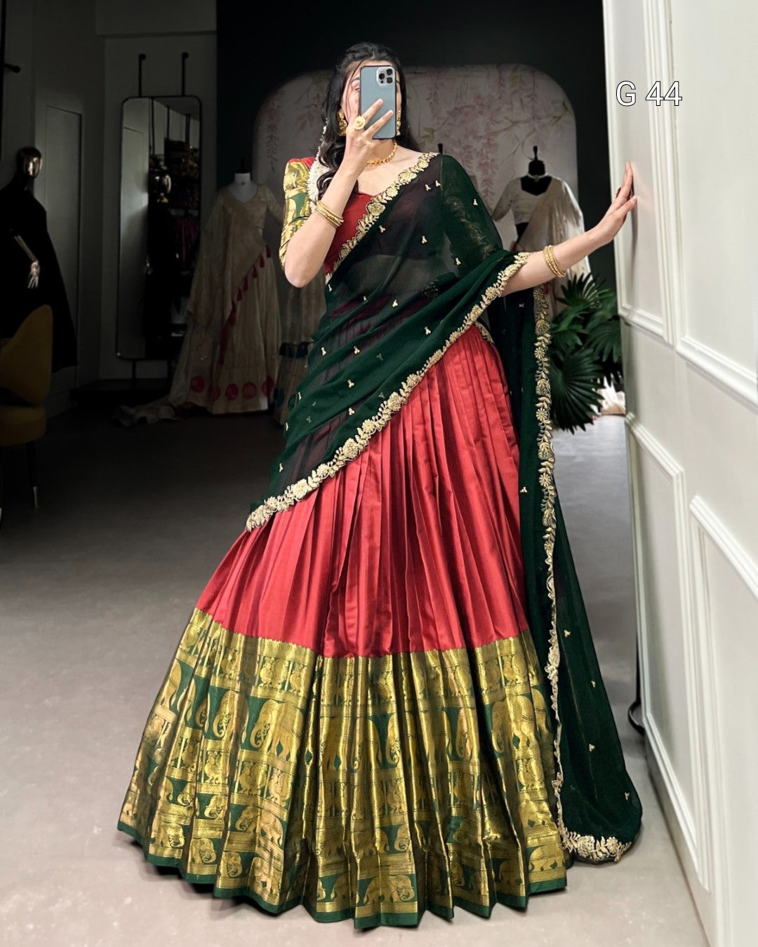 Person wearing a traditional saree with red, green, and black colors in a room.