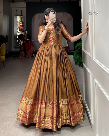 Woman taking a mirror selfie wearing a traditional brown and gold dress.
