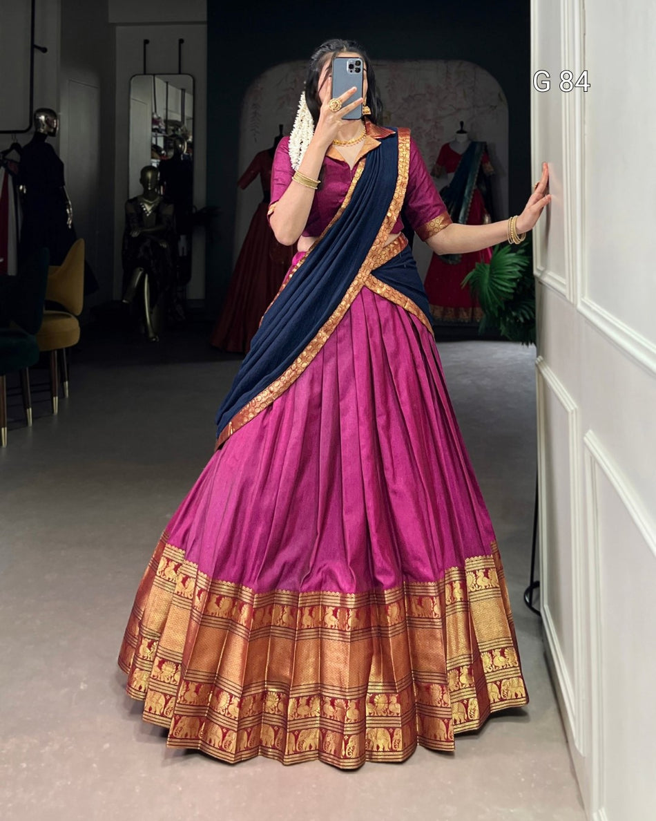 Person wearing a traditional pink and blue saree with a gold border in a room.
