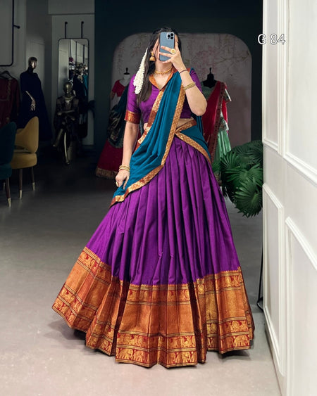 Person wearing a traditional purple saree with blue blouse in a room.