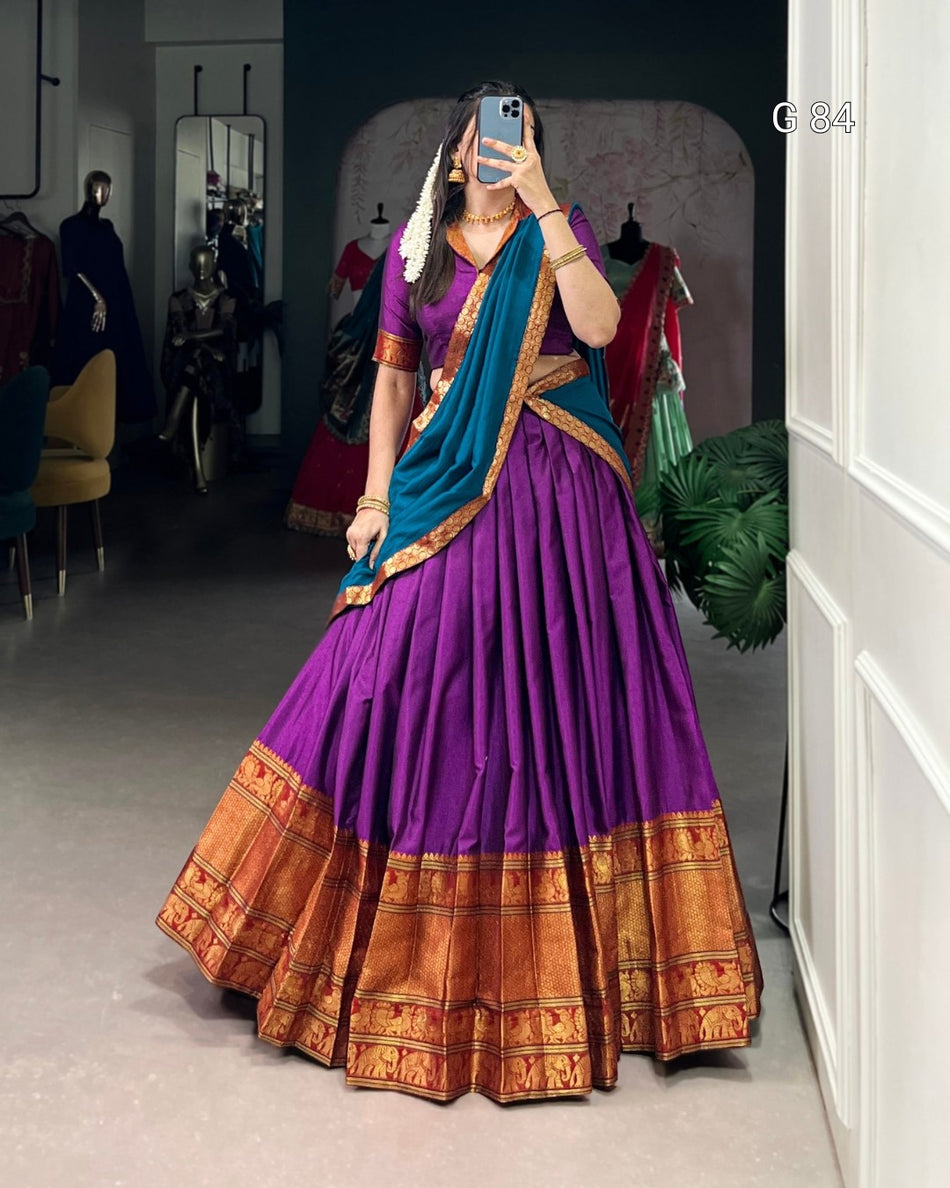 Person wearing a traditional purple saree with blue blouse in a room.