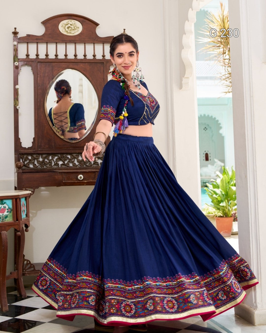 Woman wearing a traditional blue outfit with colorful patterns in a room.