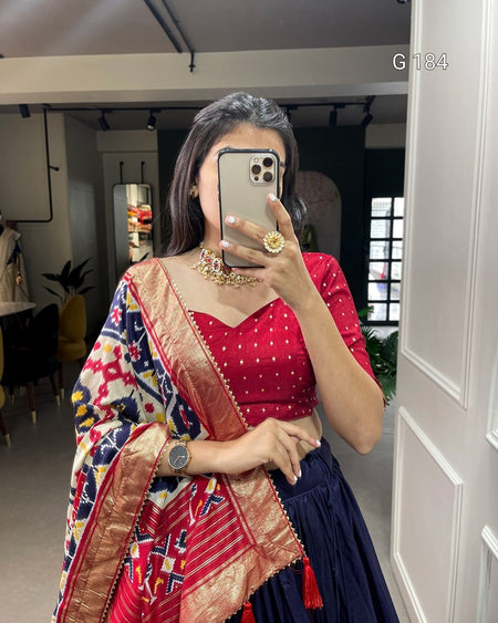 Person wearing a red blouse with a colorful saree in a room.