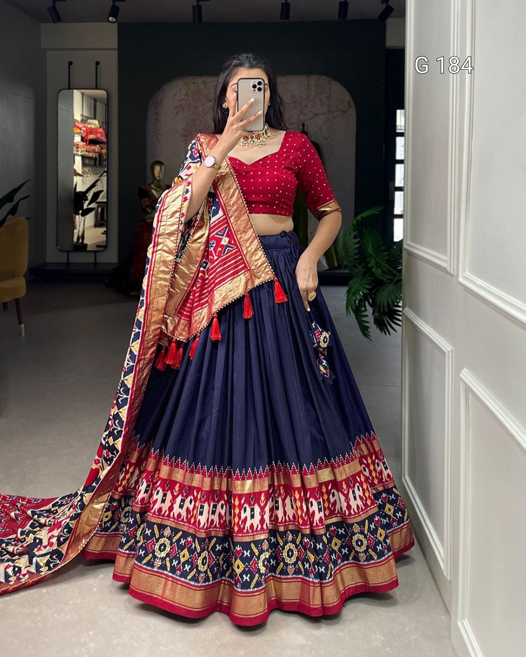Woman in a traditional outfit with a colorful dupatta taking a mirror selfie.