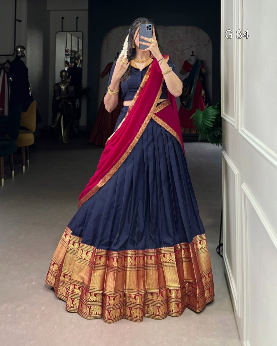 Woman wearing a traditional navy blue and red saree with gold border in a room.