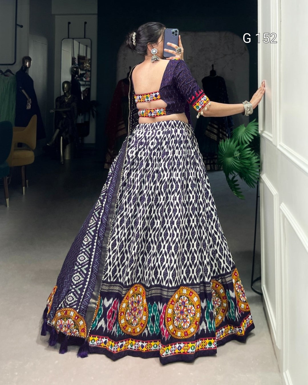 Woman in a traditional outfit with intricate patterns taking a mirror selfie.