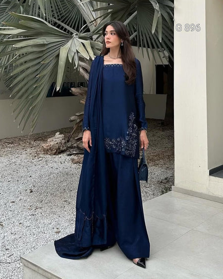 Woman in a navy blue outfit with floral embroidery standing outdoors.