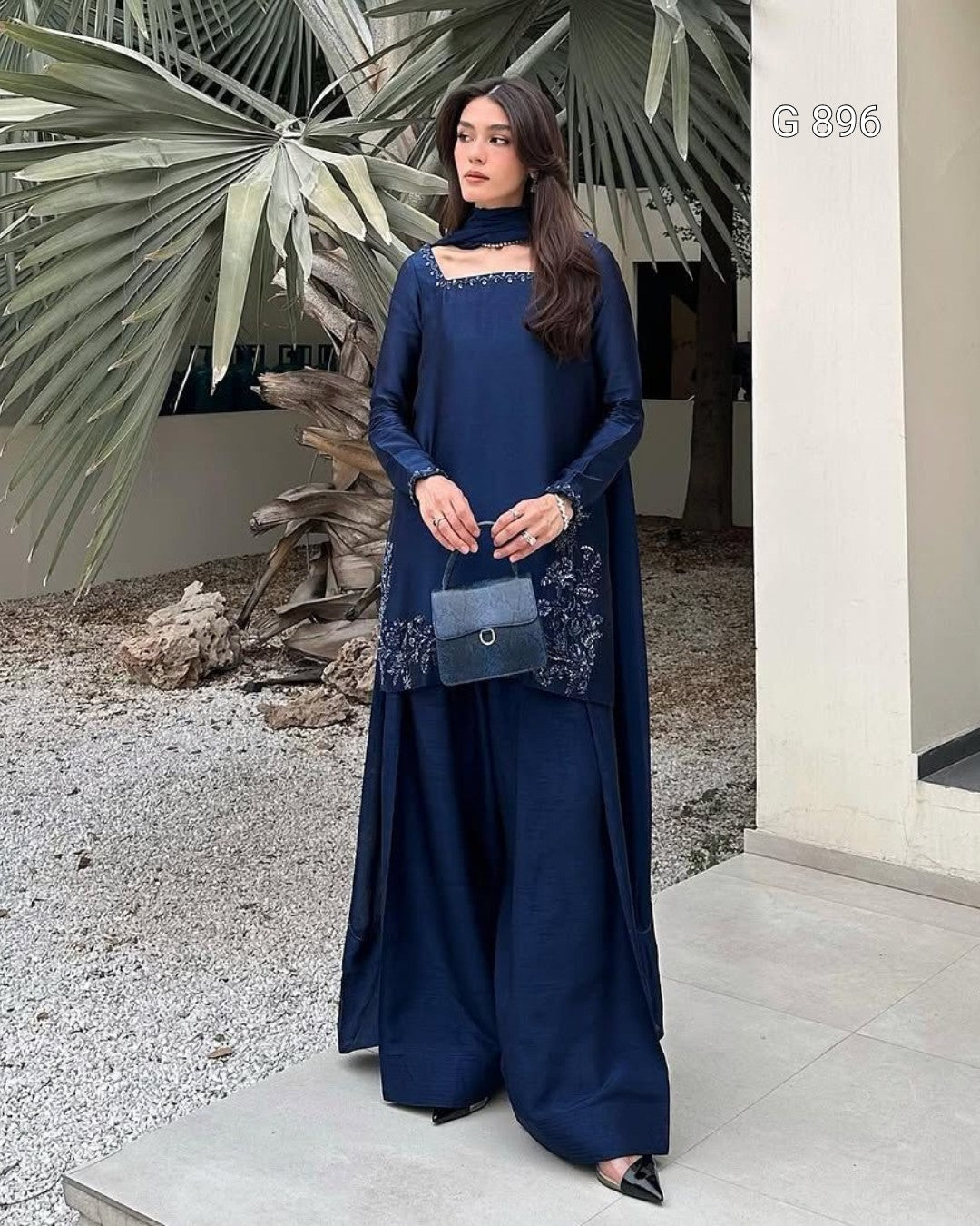 Woman in a blue dress standing outdoors with decorative elements.