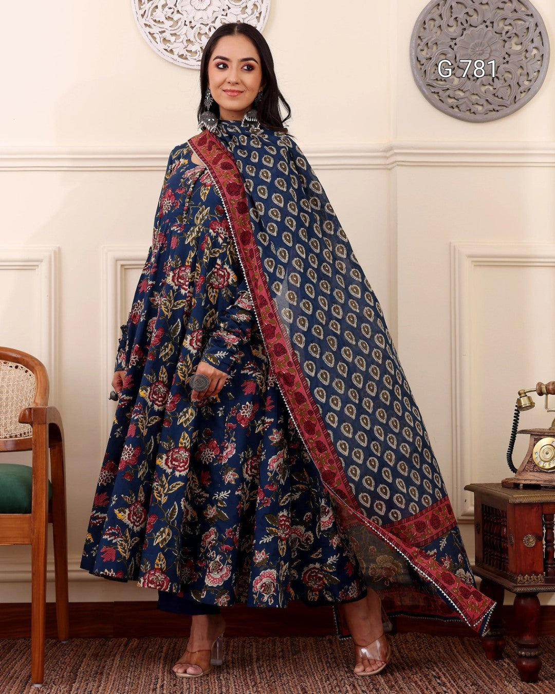 Woman wearing a traditional outfit with a floral design in a room with decorative elements.