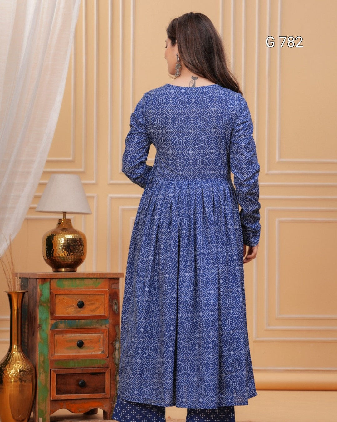 Woman wearing a blue patterned dress in an elegant room with decorative elements.