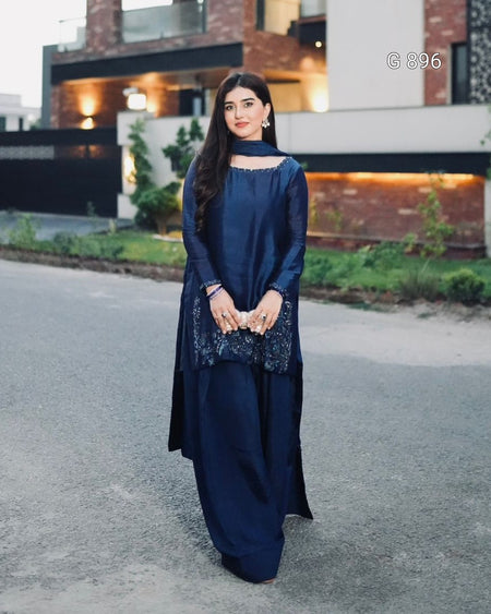 Woman in a blue traditional outfit standing on a road with a building in the background