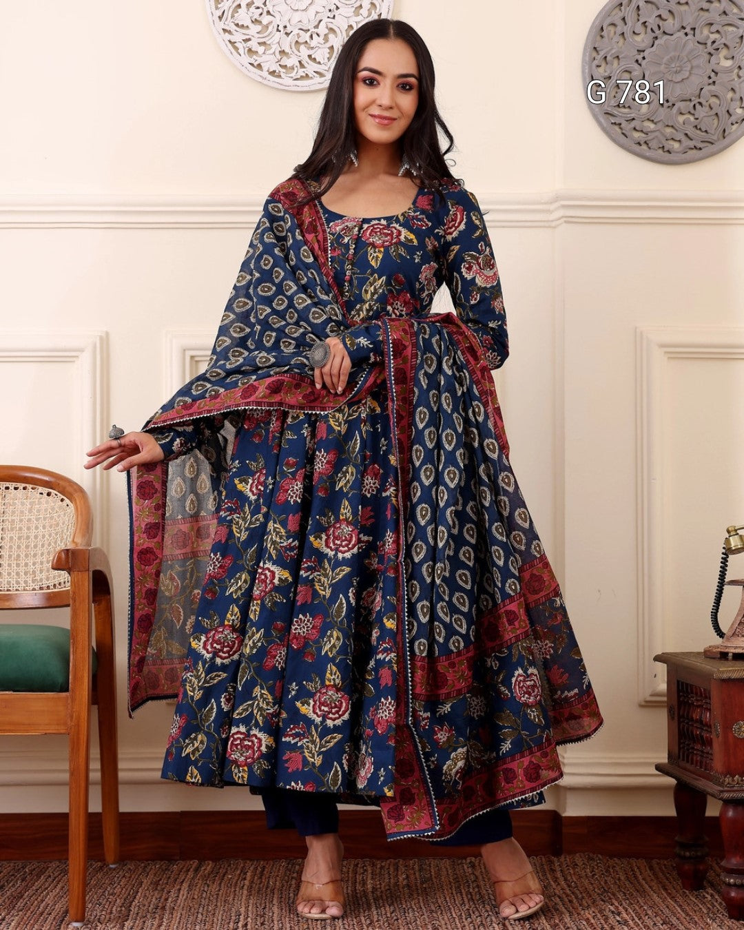 Woman wearing a long, patterned dress in a room with decorative elements.