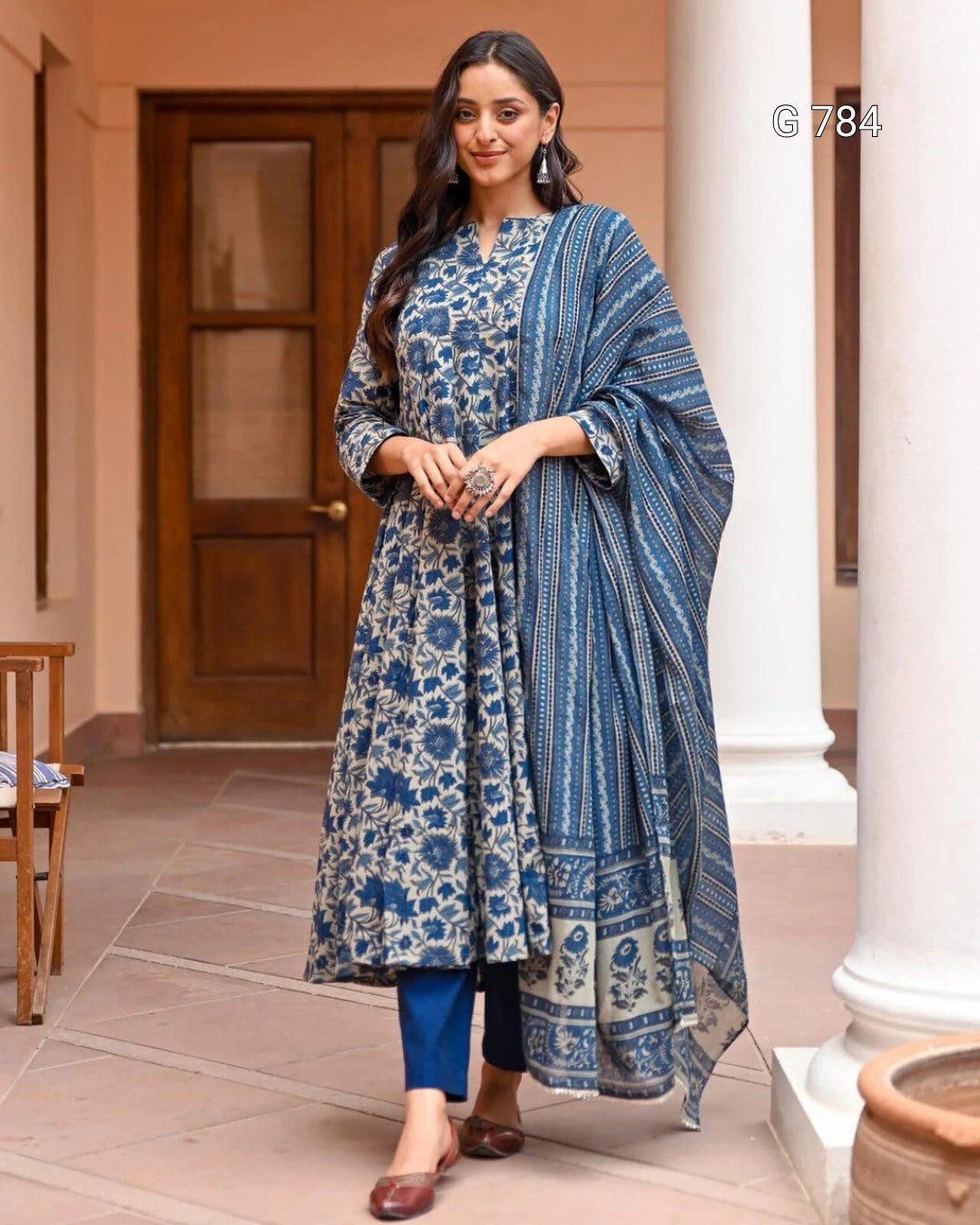 Woman in a blue floral traditional outfit standing outdoors.