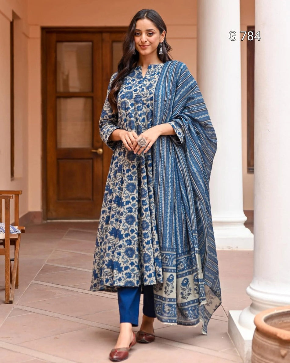 Woman in a blue floral traditional outfit standing outdoors.