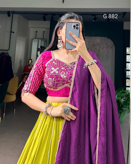 Woman taking a mirror selfie wearing a colorful traditional outfit with a pink blouse, yellow skirt, and purple dupatta.