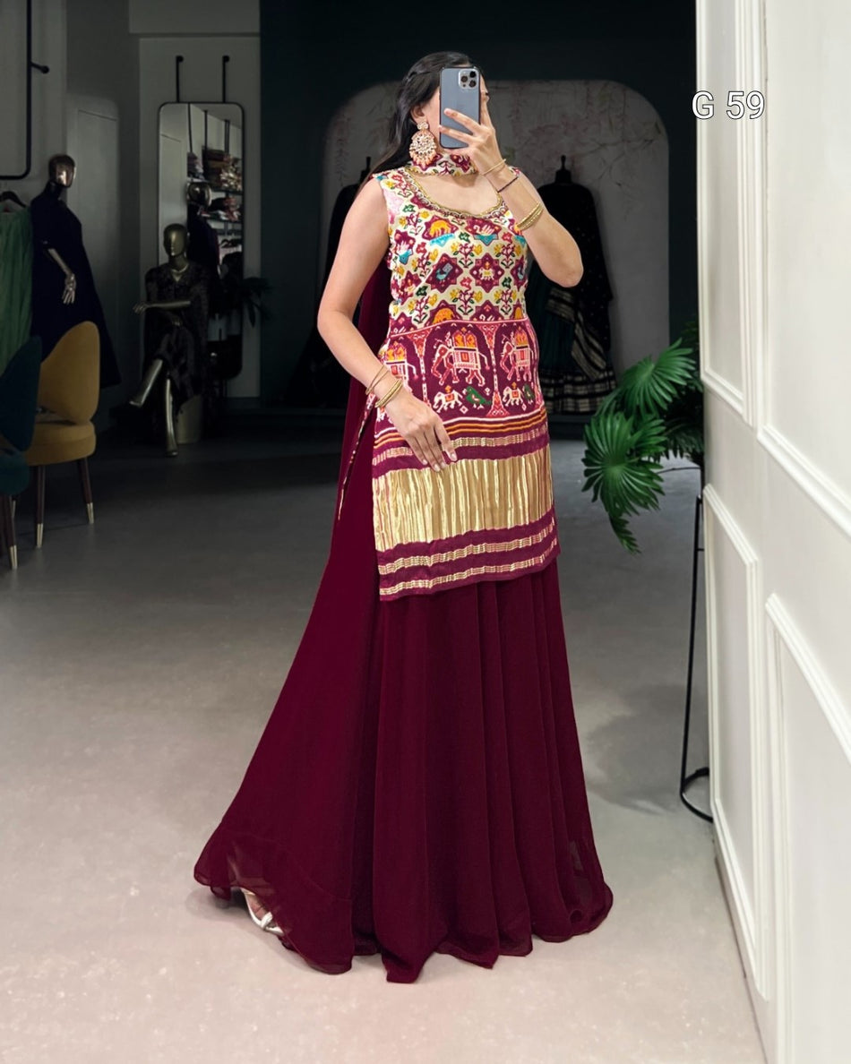 Woman wearing a colorful dress with a patterned top and maroon skirt in a room.