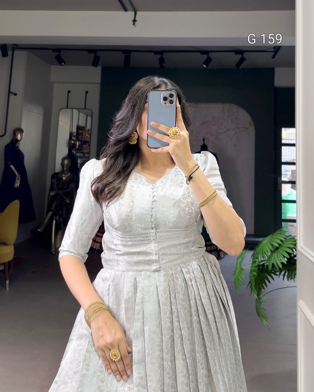 Woman taking a mirror selfie wearing a white dress in an indoor setting.