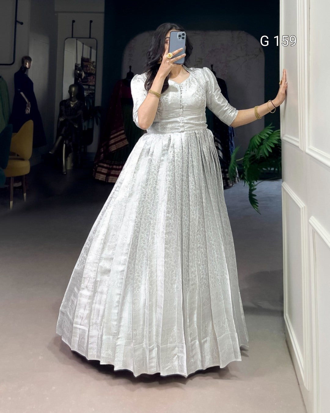 Person wearing a white dress taking a mirror selfie in a room.