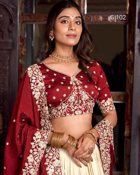 Woman wearing a traditional maroon and gold saree with jewelry indoors.