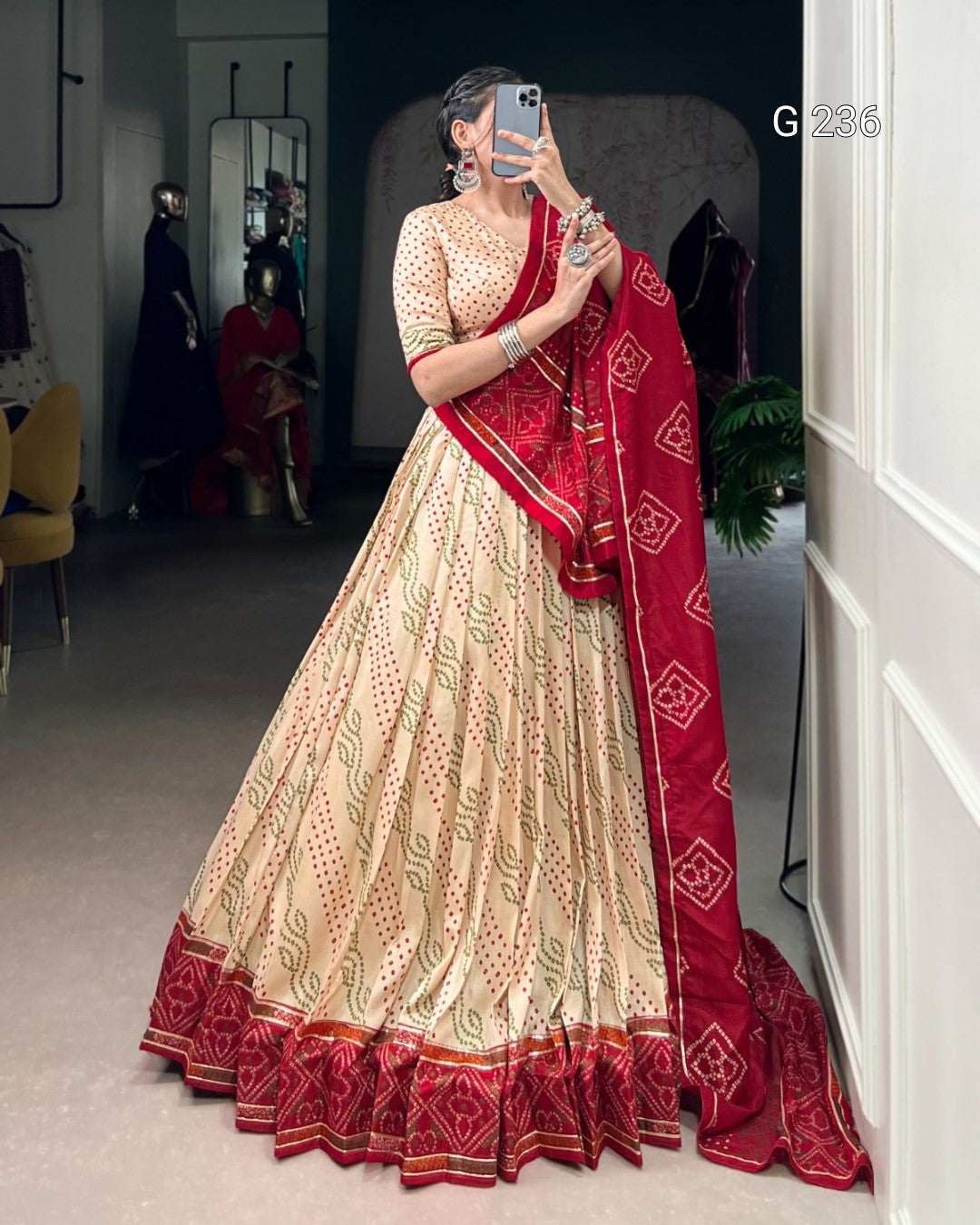 Woman in a traditional outfit with a red dupatta taking a mirror selfie.