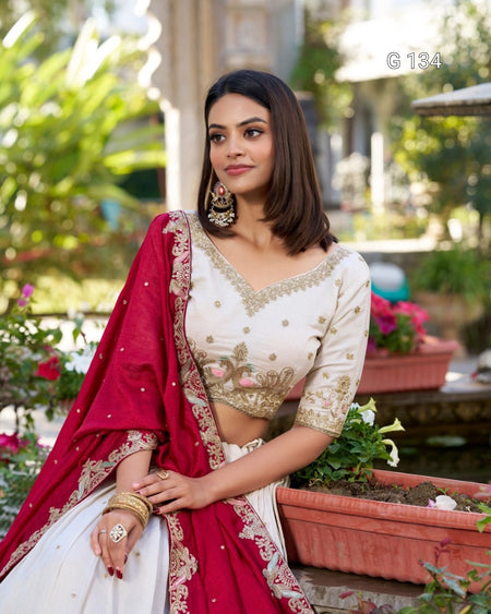 Woman in traditional white and red saree with floral patterns in a garden setting