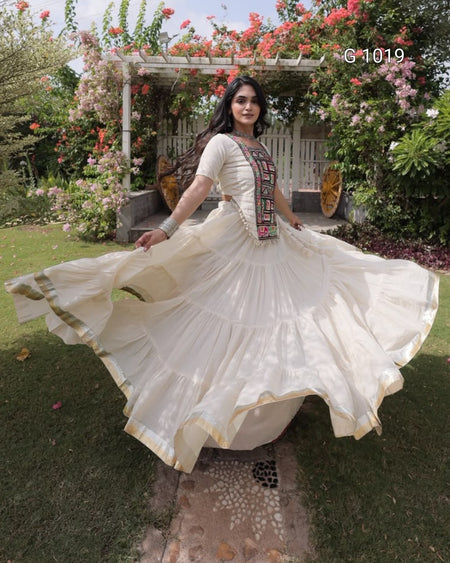 A woman outdoors in a lush garden wearing a flowing cream-colored traditional dress with a flared skirt and embroidered neckline, captured mid-spin as the fabric spreads wide.