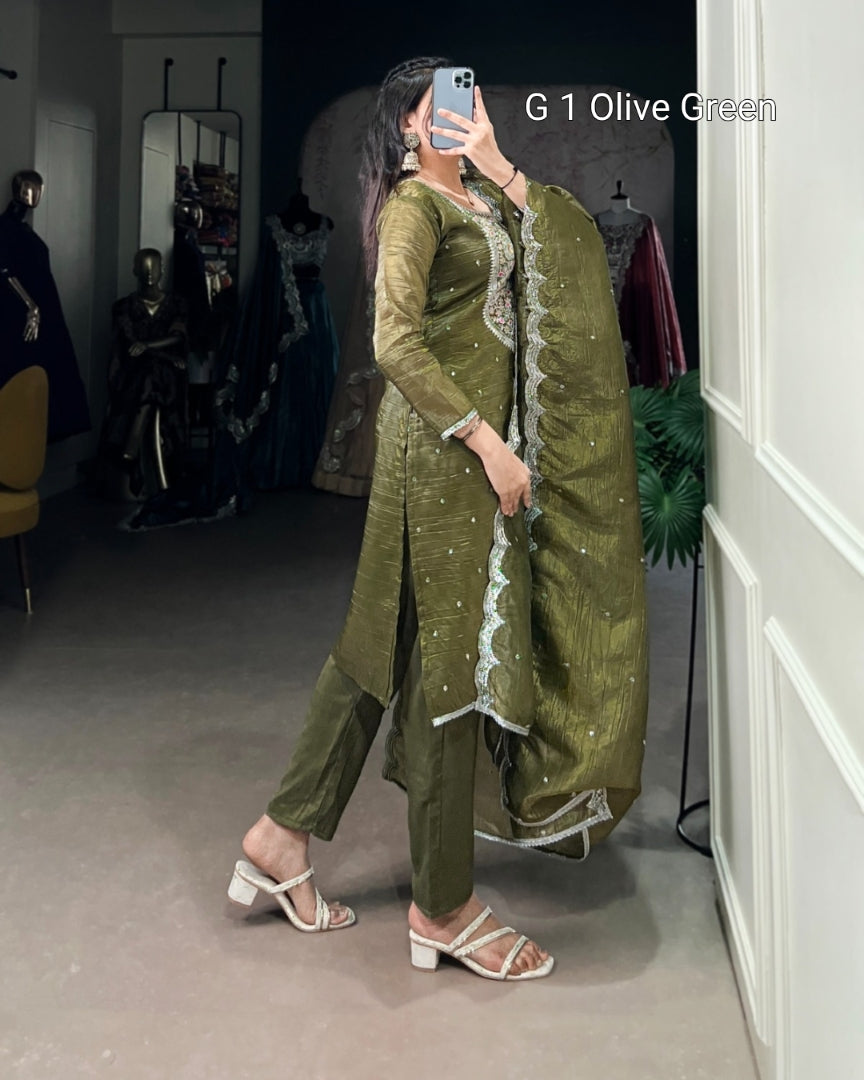 Person wearing an olive green traditional outfit with a matching dupatta in a room.
