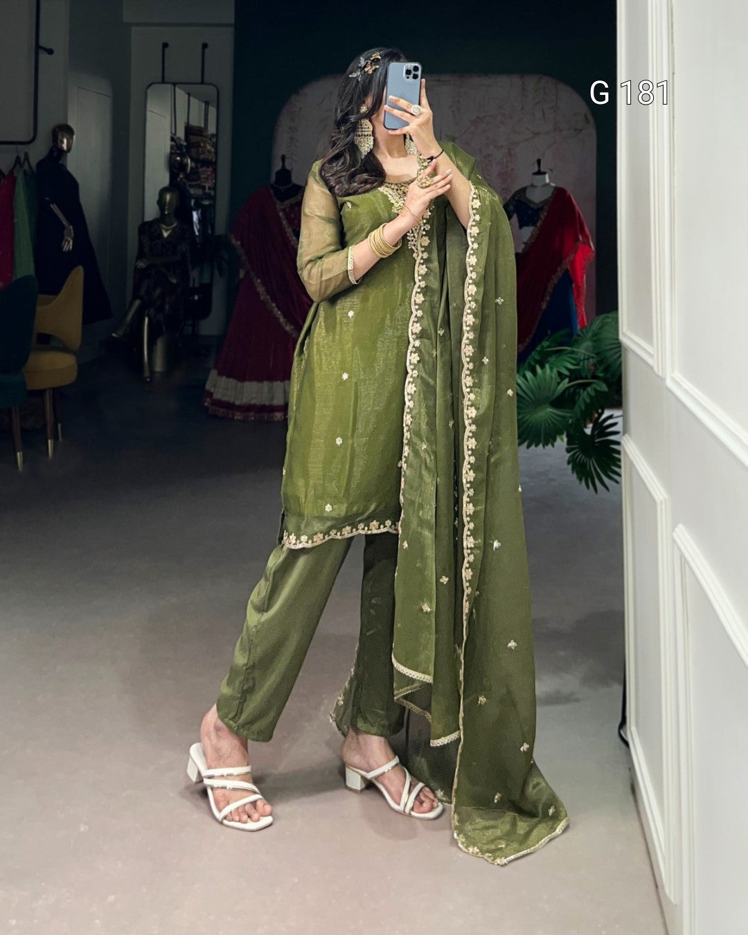 Person wearing a green traditional outfit with a matching dupatta, taking a mirror selfie.