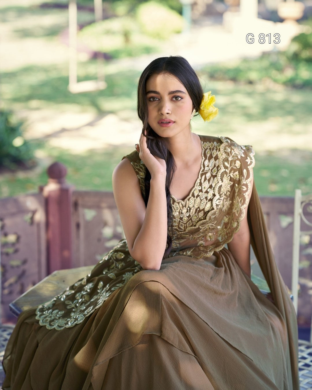 Woman in a green and gold dress sitting outdoors with blurred background
