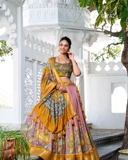 Woman in a traditional outfit with a yellow and pink design, standing in front of a white architectural structure.