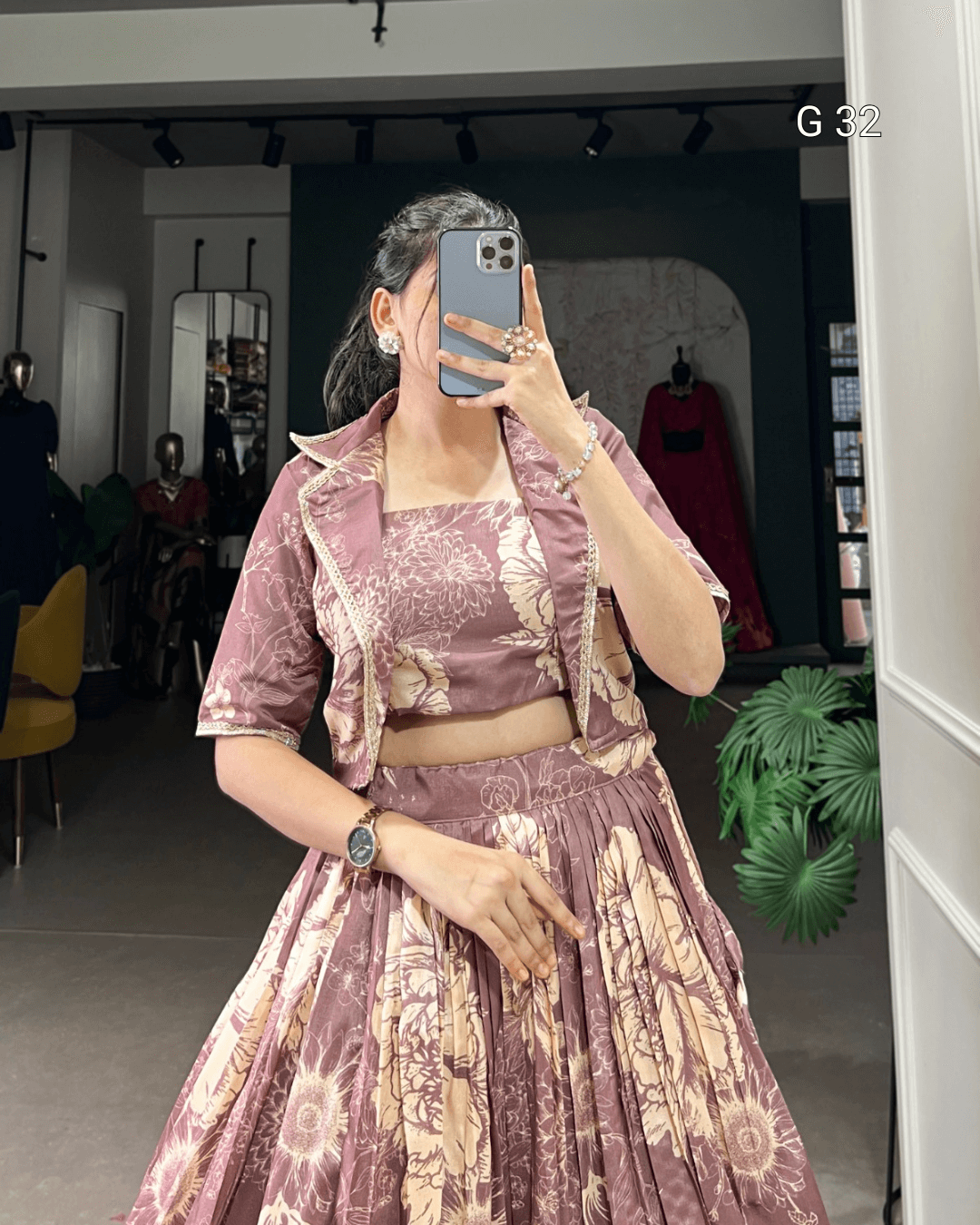 Person wearing a patterned outfit taking a mirror selfie in a store.