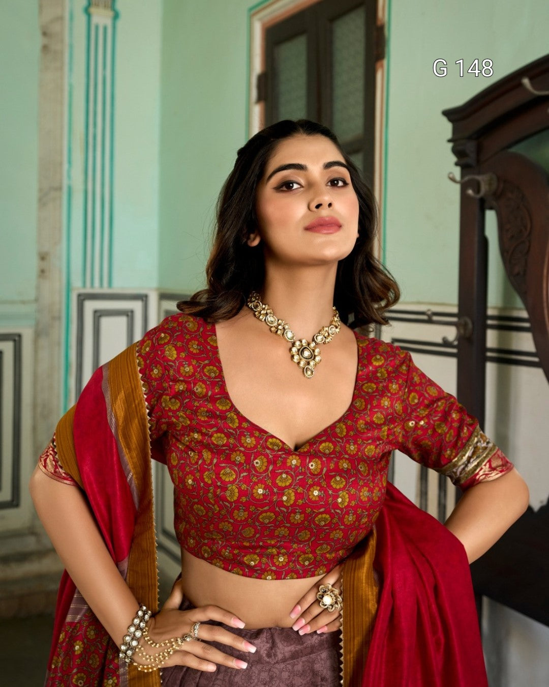 Woman wearing a red and gold traditional outfit with jewelry indoors.
