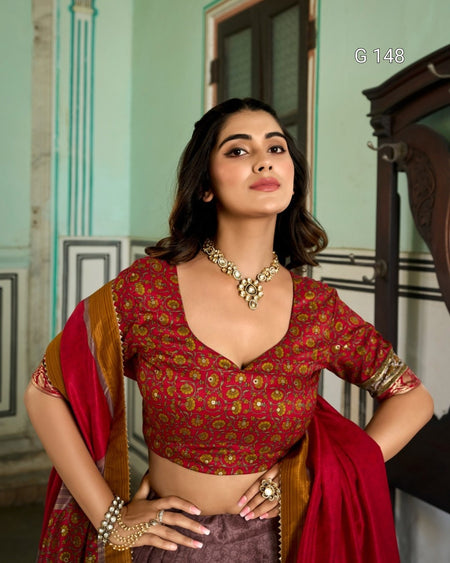 Woman wearing a red and gold traditional outfit with jewelry indoors.