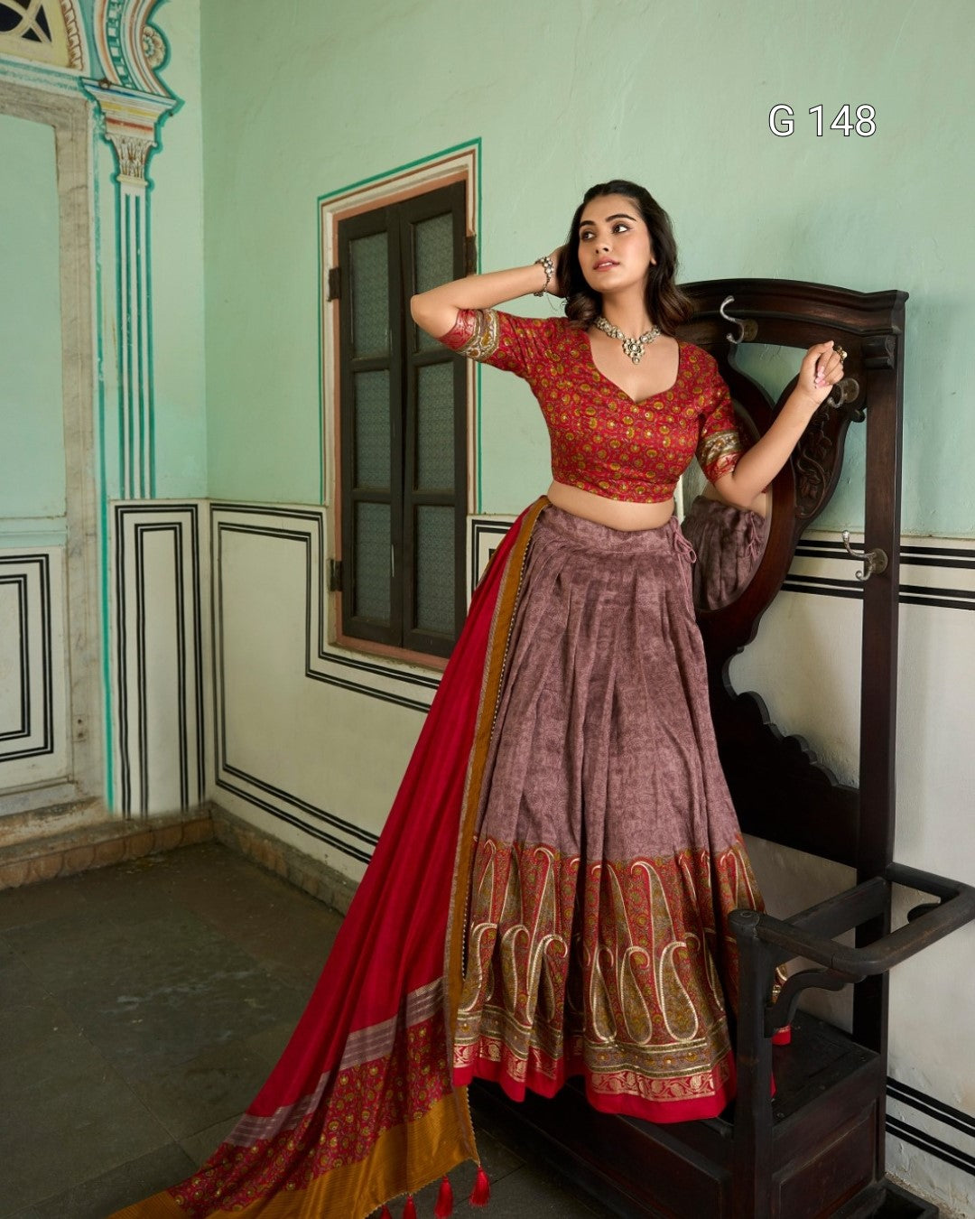 Woman in traditional red and brown outfit standing in a decorated room.