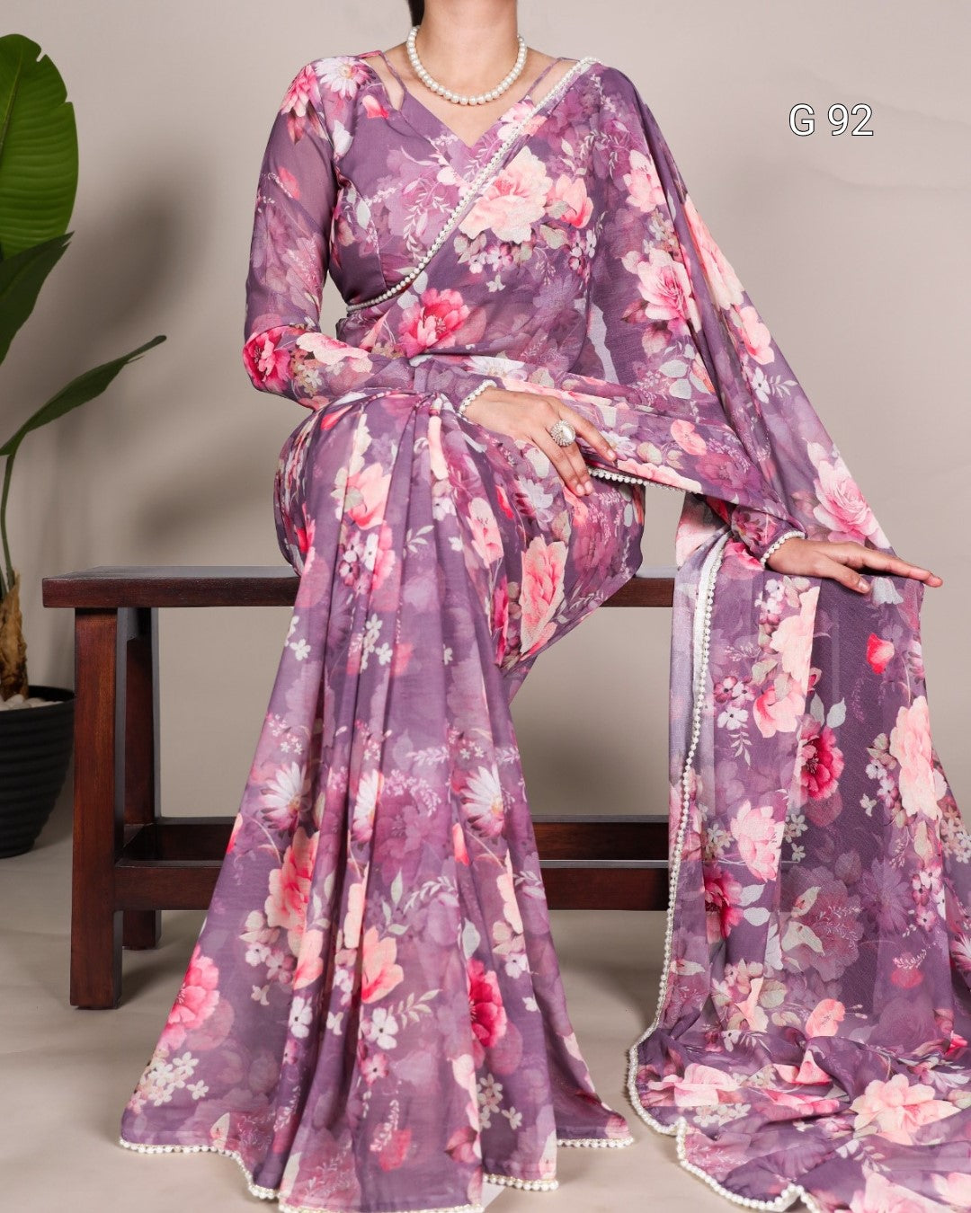 Purple floral saree with a matching blouse draped over a person, against a neutral background.