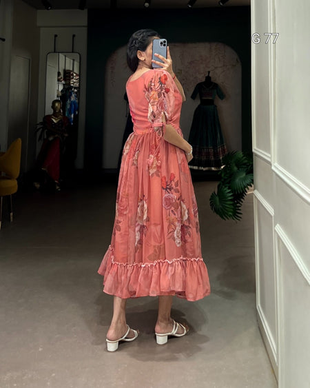 Person wearing a pink floral dress taking a mirror selfie in a room.