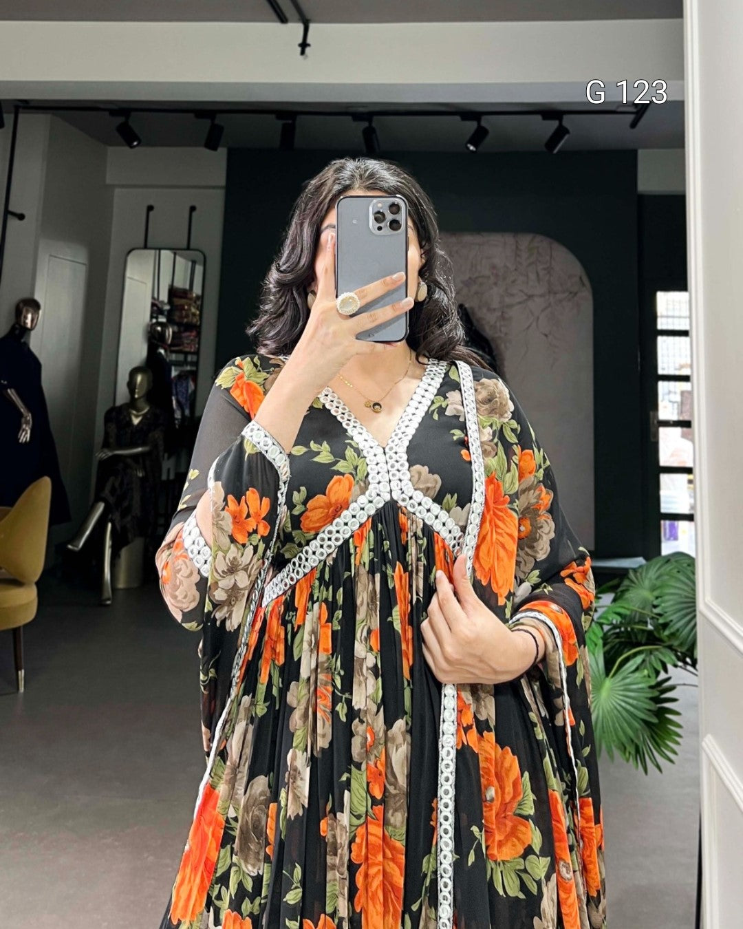 Person wearing a floral dress with a measuring tape around their waist in a room.