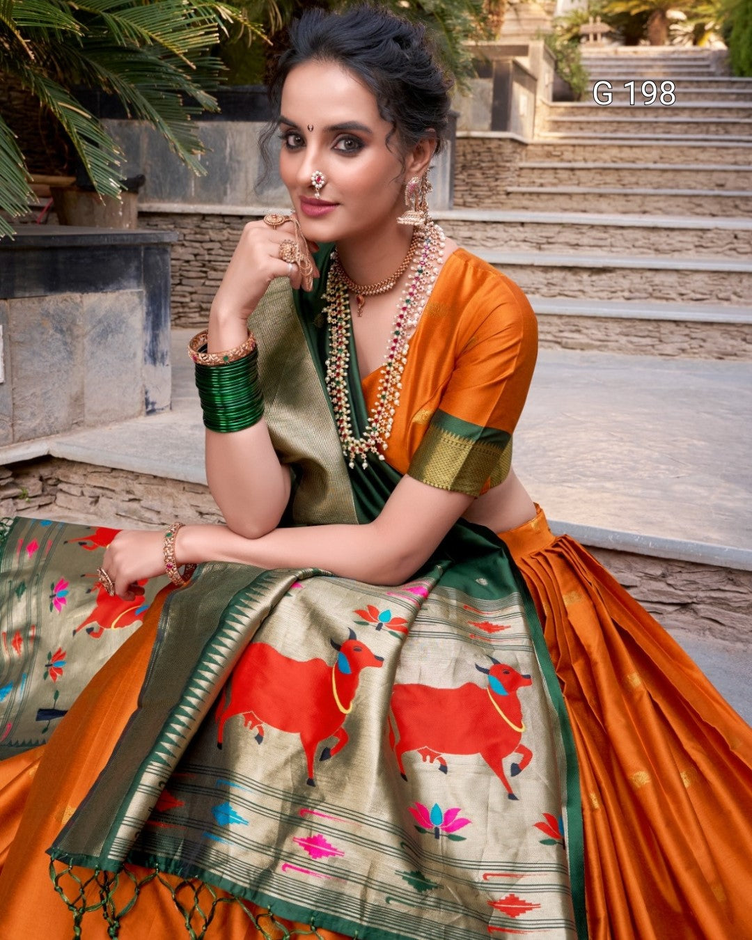 Woman in traditional saree with decorative elements sitting outdoors.