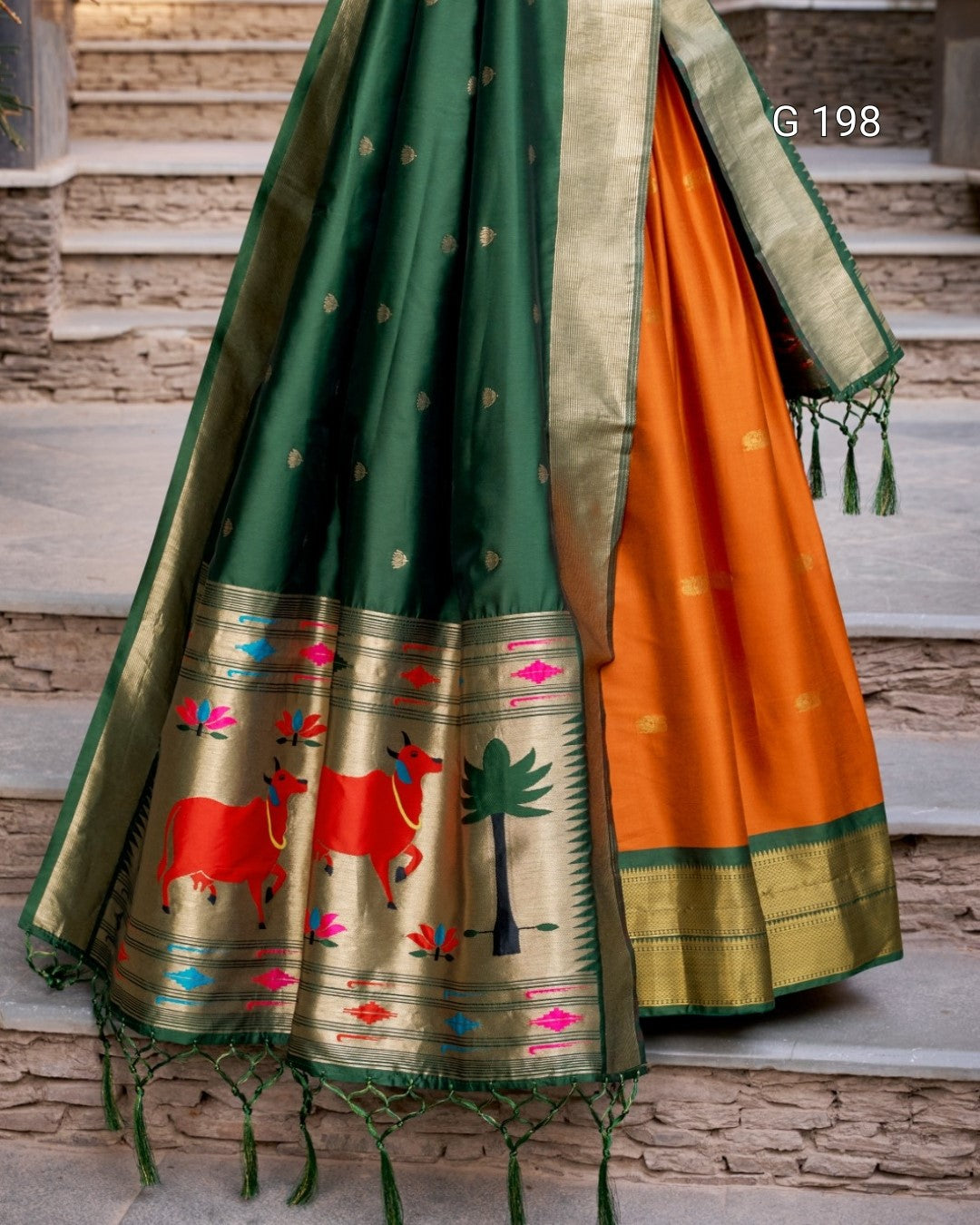 Traditional saree with green and orange patterns on a stone staircase background
